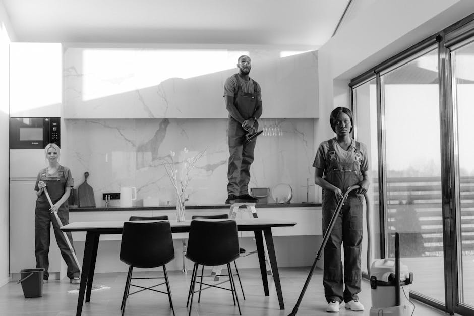 Two professional cleaning staff members from Hammersmith Cleaner are preparing their equipment outdoors on a paved surface, likely during a commercial or residential cleaning job. The woman on the lef